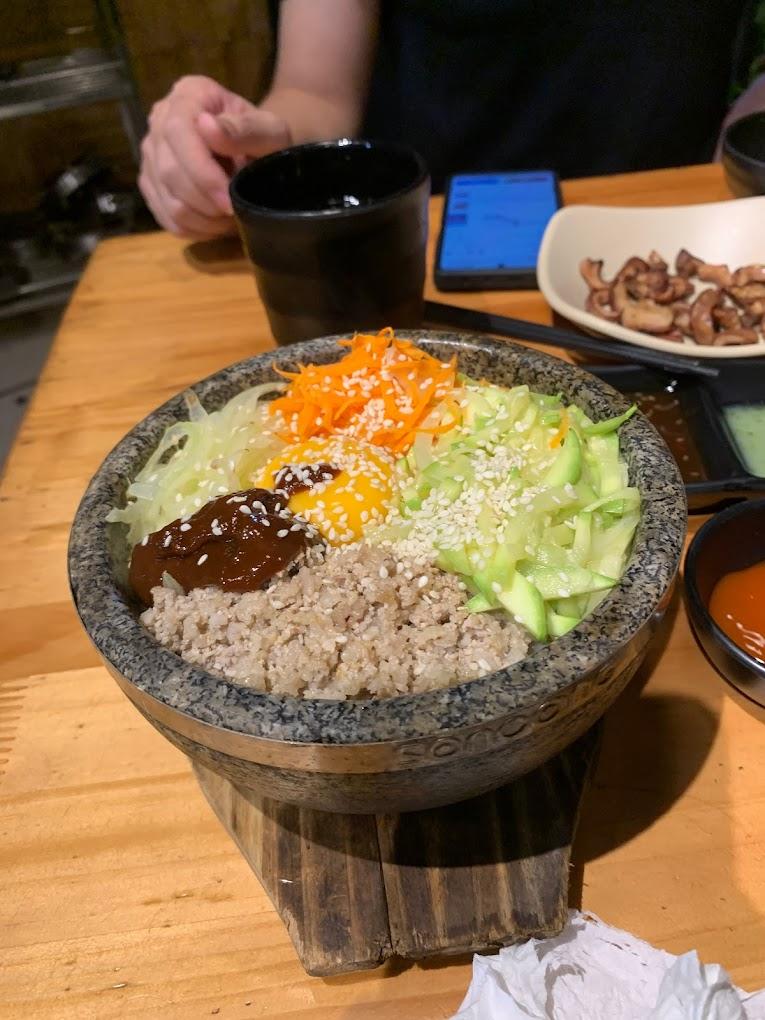 Món cơm trộn Hàn Quốc, còn được gọi là Bibimbap, là một sự kết hợp giữa cơm, rau củ tươi ngon và thịt hoặc hải sản, thường được kèm theo trứng sống hoặc chiên. Khi thưởng thức, bạn sẽ cảm nhận được sự hài hòa giữa hương vị đa dạng của các thành phần cùng với hương thơm dịu nhẹ và mùi vị đặc trưng của các loại gia vị Hàn Quốc