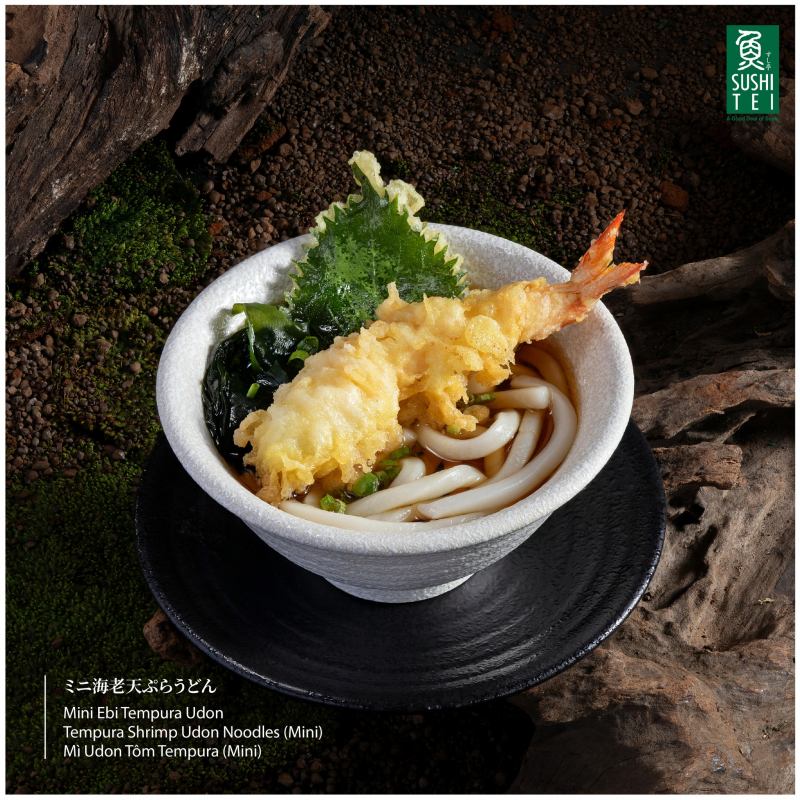 Mì Udon Tempura tại Sushi Tei Việt Nam mang đến sự kết hợp hài hòa giữa vị thanh đạm của mì udon và vị giòn tan, béo ngậy của tempura. Nước dùng dashi thanh ngọt, được ninh từ rong biển kombu và cá bào katsuobushi, tạo cảm giác nhẹ nhàng, tinh tế.